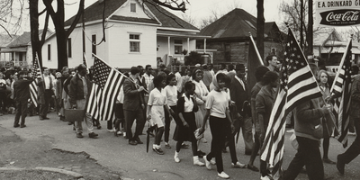 Historical image of marchers with American flags participating in the 1965 Selma to Montgomery march