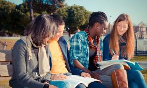 students looking over homework sitting on bench outside