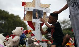 A young student writes a message on a makeshift memorial