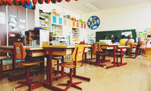 Group of students and teacher sitting near blackboard having a discussion.