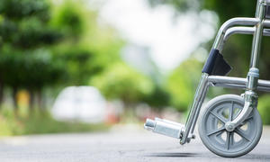 Empty wheelchair parked on what appears to be either a sidewalk or road.