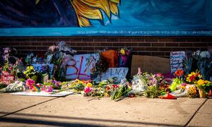 Signs with "Black Lives Matter" and "BLM" laid on the ground with flowers.