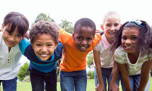 Five children leaning in toward the camera demonstrating community.