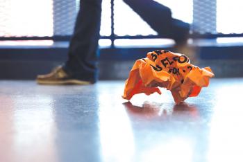 Orange crunched piece of paper on the floor while students pass by